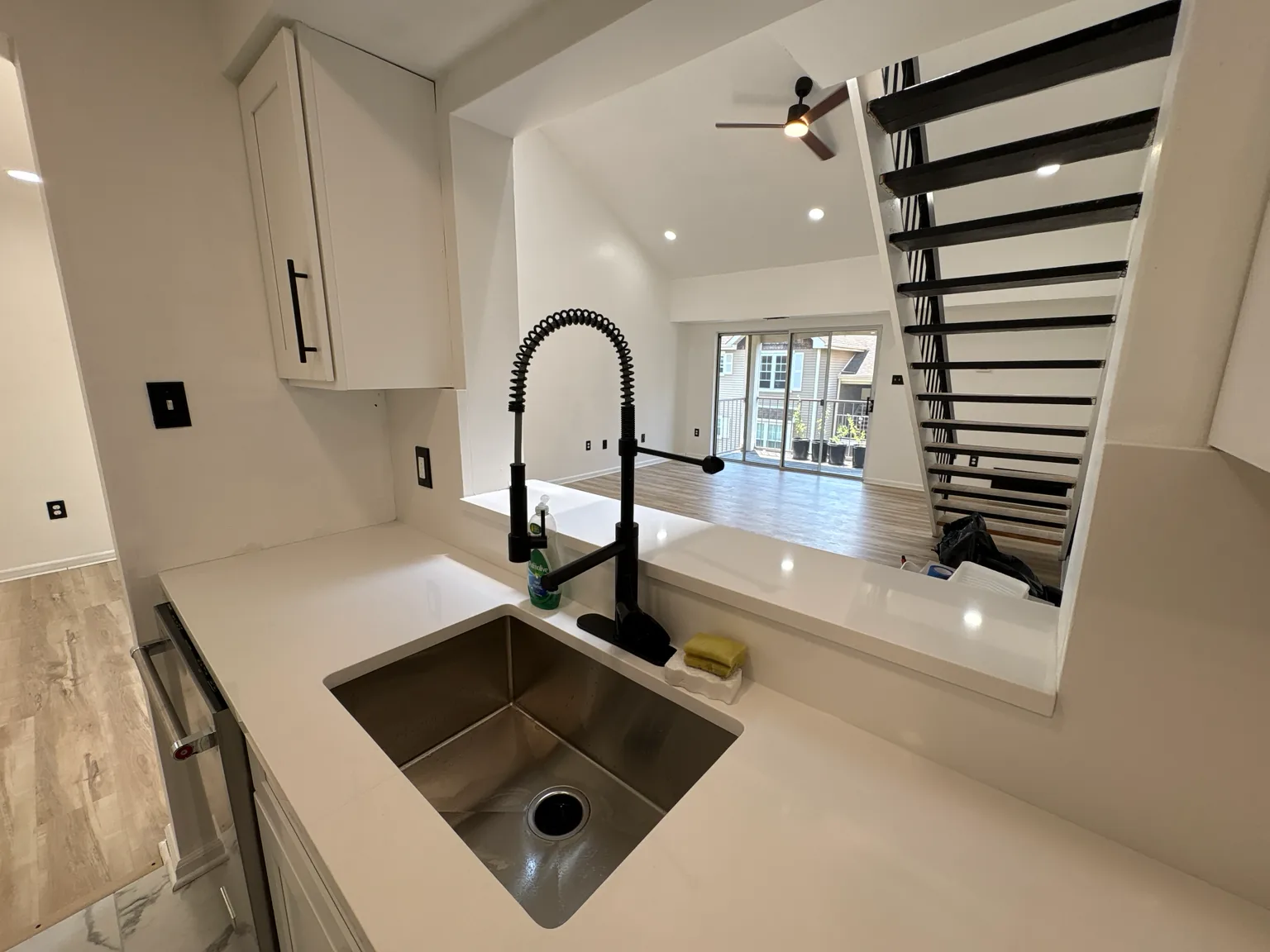 Completed interior renovation with new flooring and black stair railing by Safe Build Pros